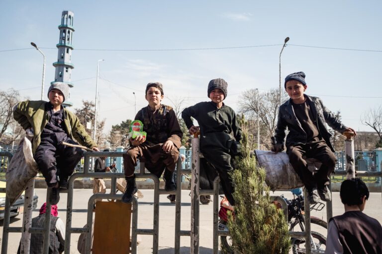 Afghan children sitting on a barrier, taking a break from their respective work in Mazar-i-Sharif, Afghanistan.