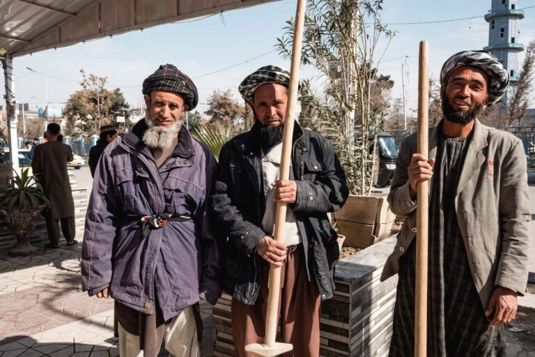 Group of Afghan men in traditional clothing conversing on a bustling street in Mazar-i-Sharif, Afghanistan