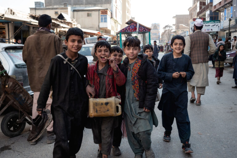 Group of Afghan boys walking through a lively street market in Kunduz, Afghanistan.