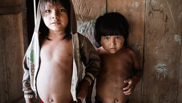 Two Achuar children standing close, gazing curiously at the camera, Amazon rainforest
