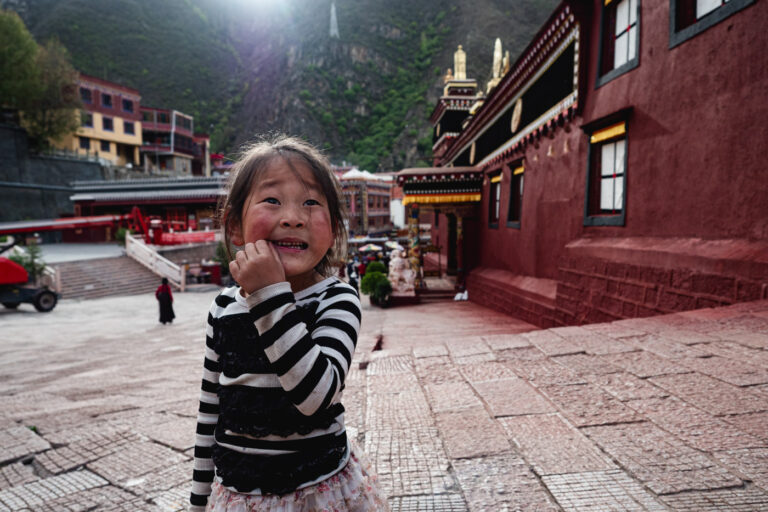 Smiling child on a monastery path in rural China in the city Dege