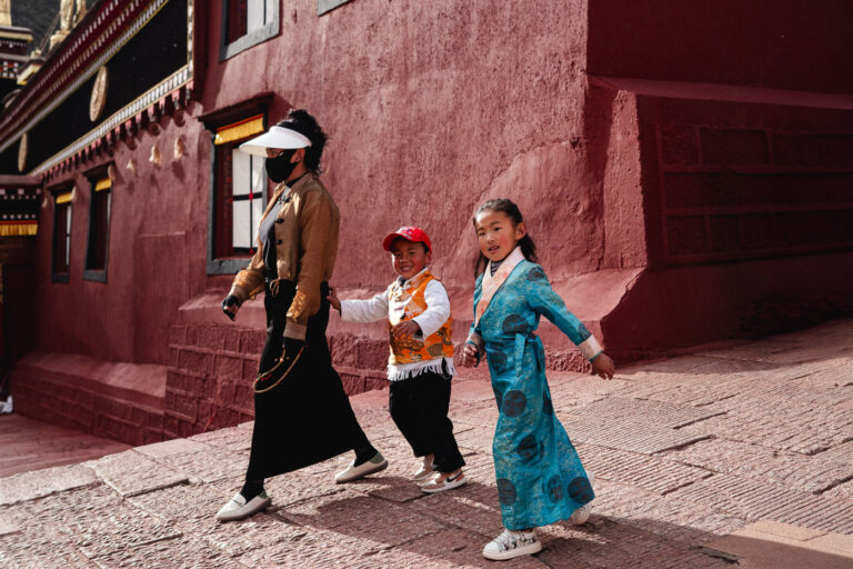 Tibetan mother and two kids praying around printing house in sichuan dege china