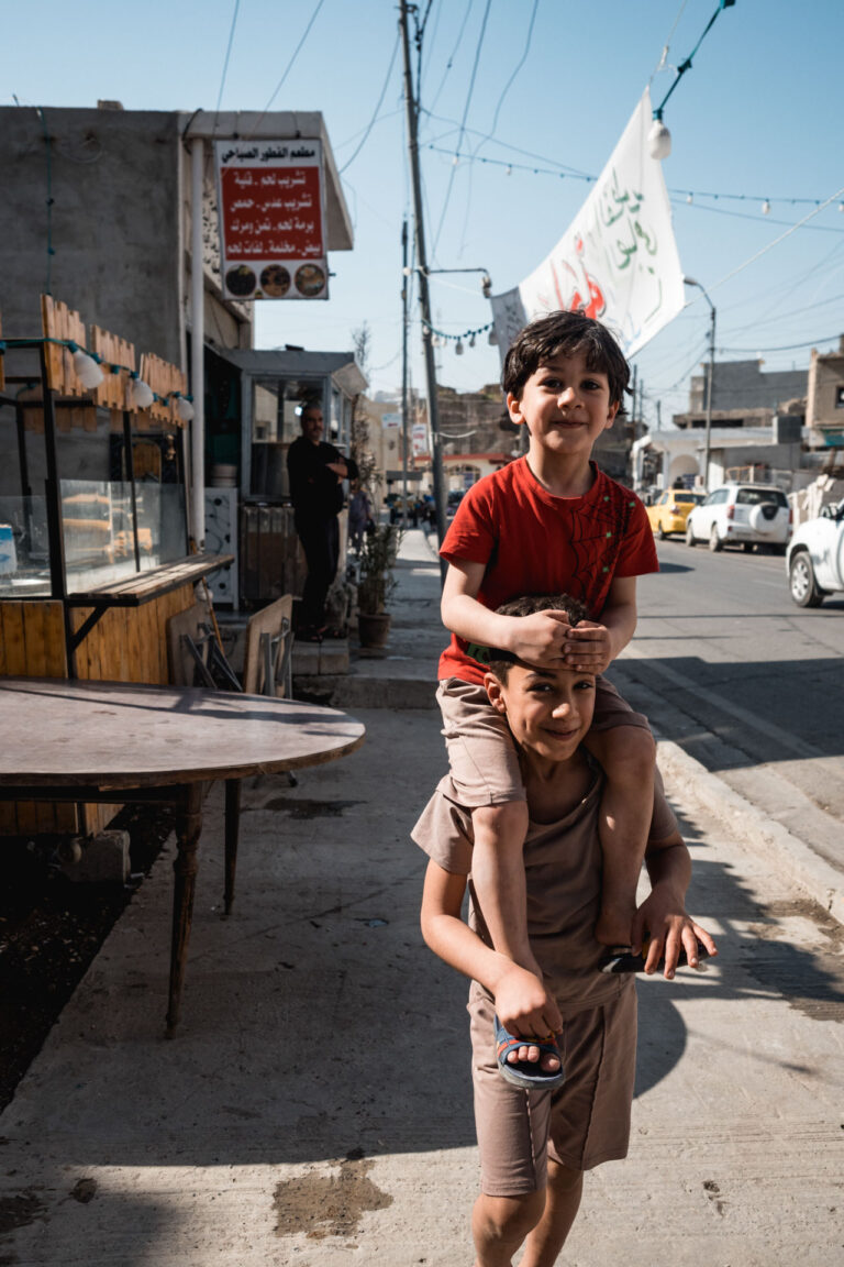 Iraqi child wearing traditional clothes, walking down a rebuilt street in Mosul’s old town.