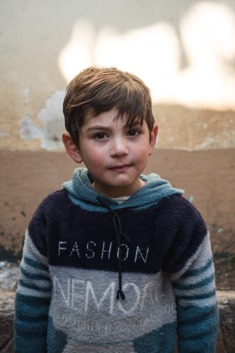 Boy in a blue hoodie standing on a dusty road in the mountainous Swat Valley.
