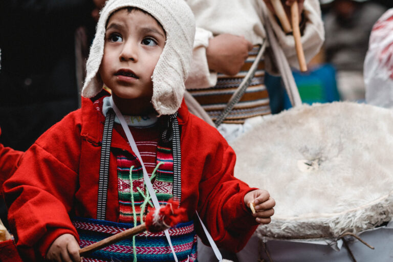 Close-up of a child dancer in a folkloric costume playing drums, celebrating the vibrant Fiesta de la Candelaria.