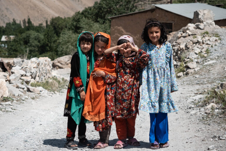 Group of Tajik children walking in colorful clothing through a mountainous path at Seven Lakes.
