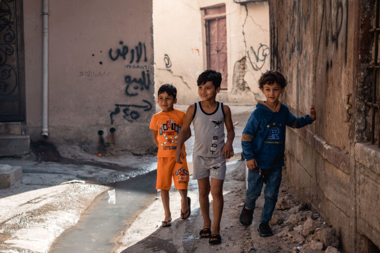 Three children playing happily in Mosul’s damaged yet resilient neighborhoods