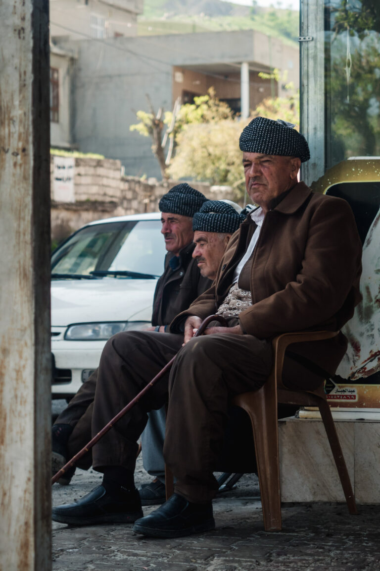 Elderly kurdish men sitting on a bench in a quiet street of Erbil, Kurdistan