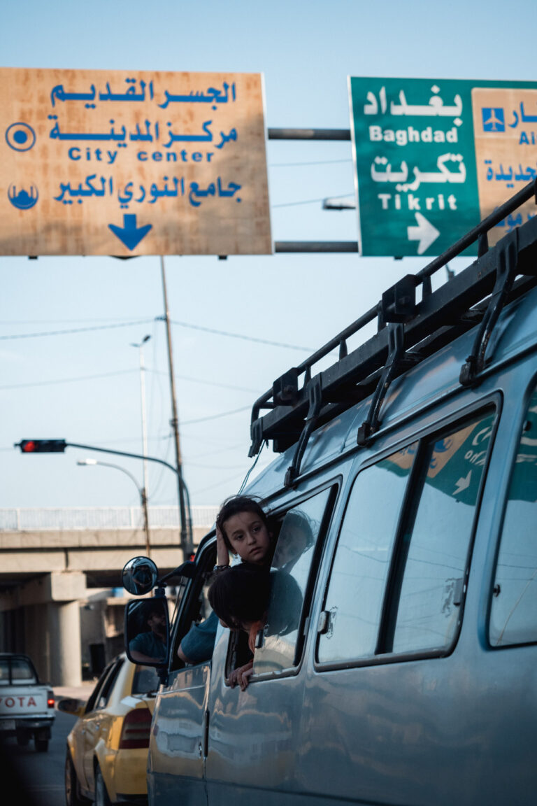Child at the window of a minivan in Mosul's traffic