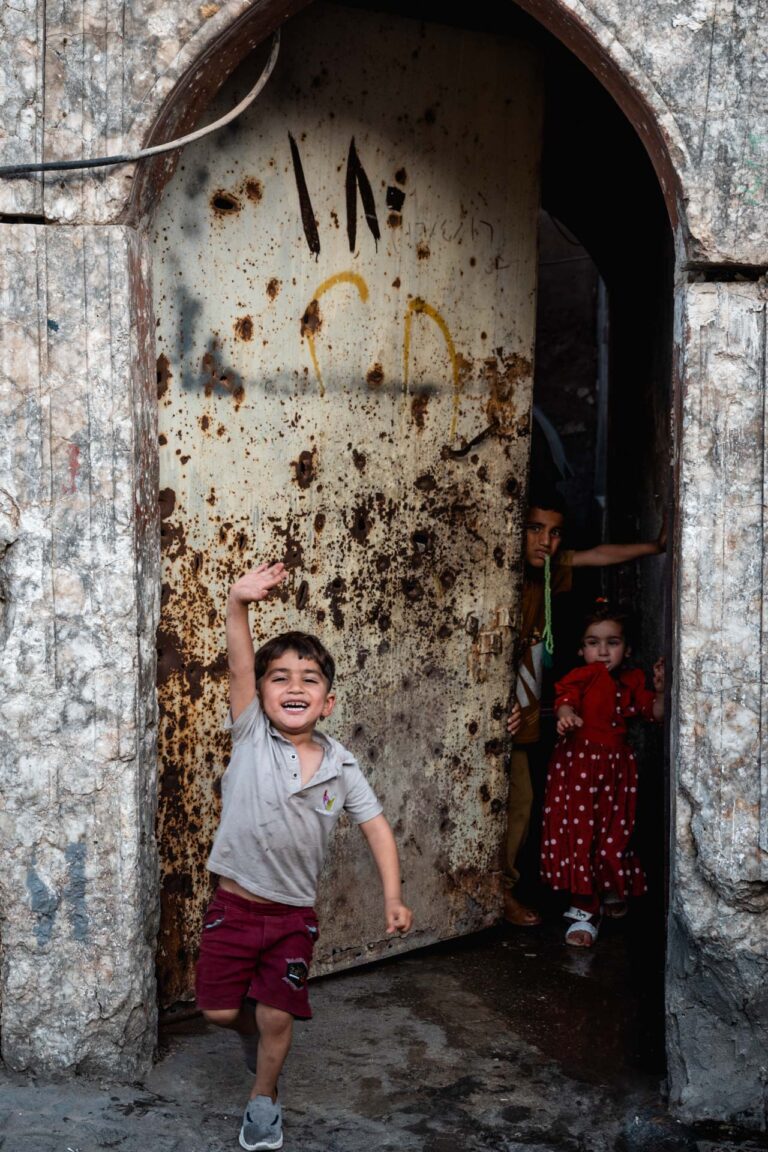 Children playing in front of a weathered door in historic Mosul neighborhood