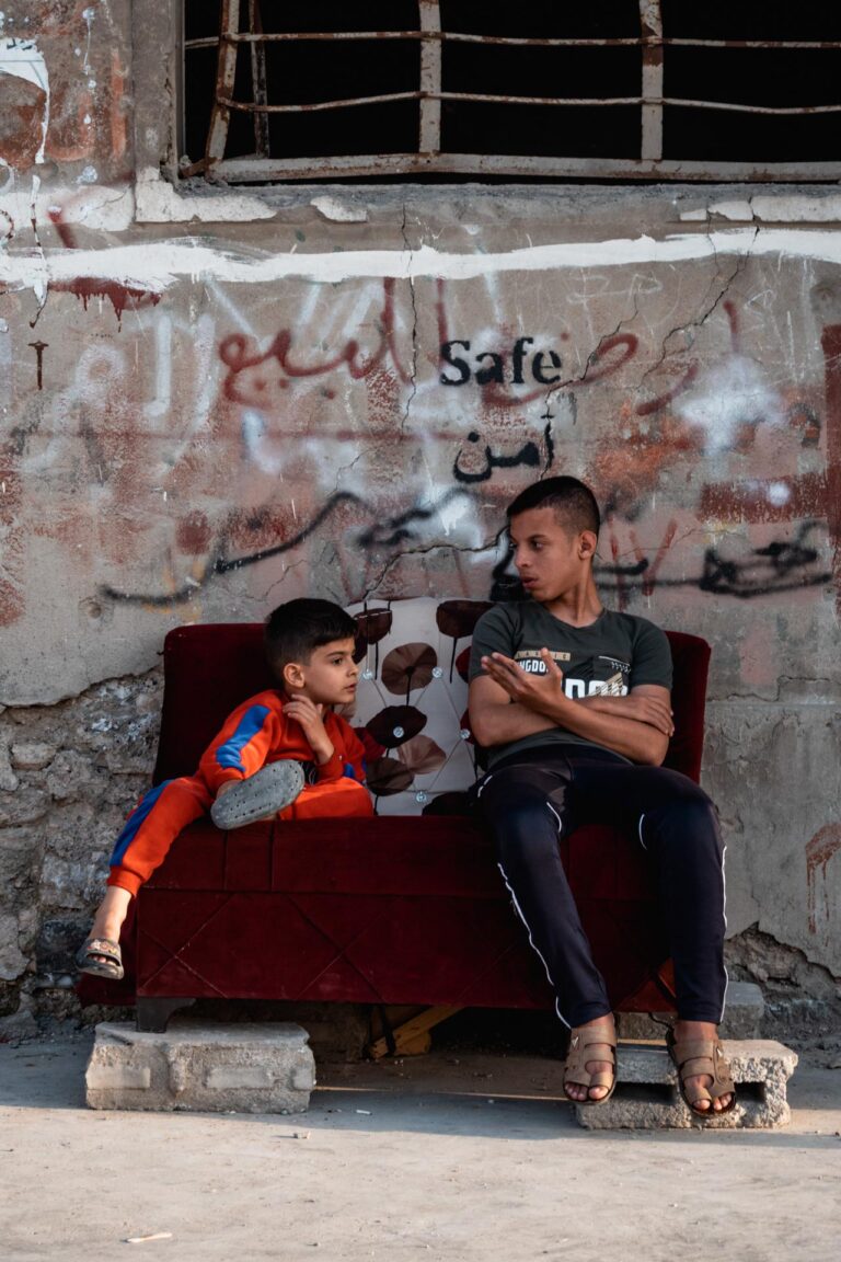 Two boys sitting against graffiti-covered walls in Mosul’s abandoned streets