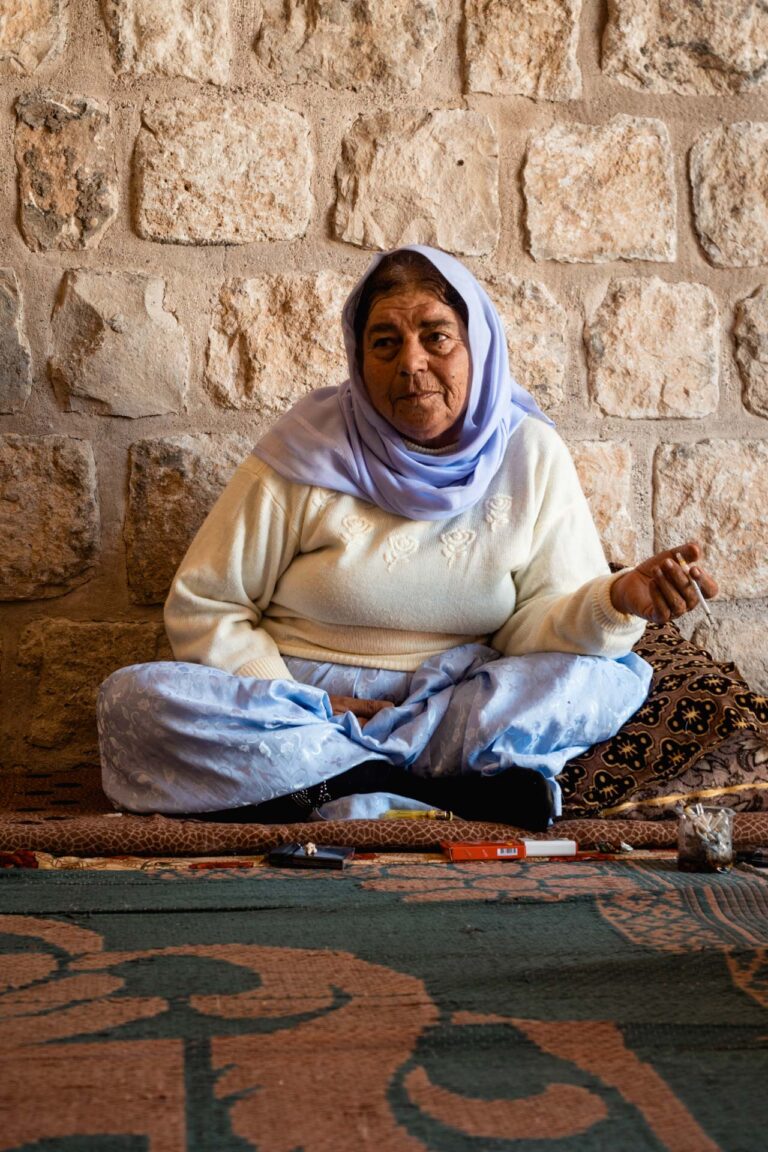 Yazidi woman dressed traditionally sitting outside the Lalish shrine, Kurdistan