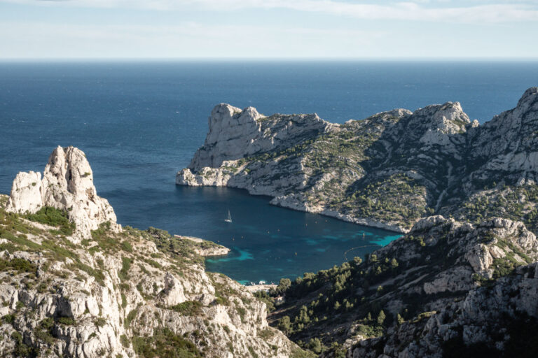 Emerald waters of Sormiou calanque surrounded by limestone cliffs in France