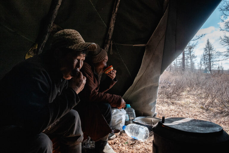 Tsaatan men sitting by fire inside their traditional ortz tent.