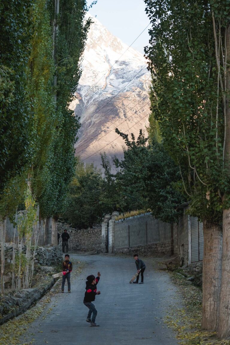 A scenic road lined with tall poplar trees cutting through Hopper village in Hunza valley, Pakistan.
