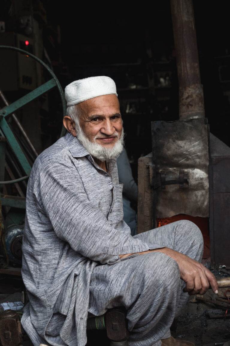A busy street scene featuring Pakistani men seated beside goods in the markets of Peshawar, Pakistan.