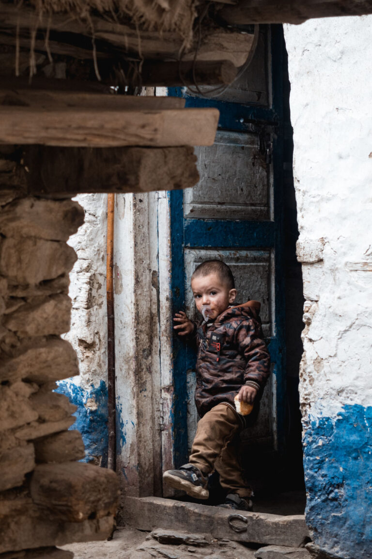 Kalash boy coming out from his house with bread in his hand, in Bumburet valley, Pakistan.