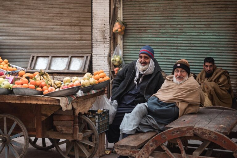 A busy street scene featuring Pakistani men seated beside goods in the markets of Peshawar, Pakistan.
