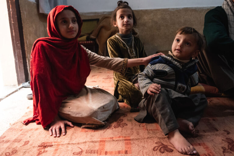 Family gathered around a small fire in a dimly lit room, keeping warm during winter in Peshawar, Pakistan.
