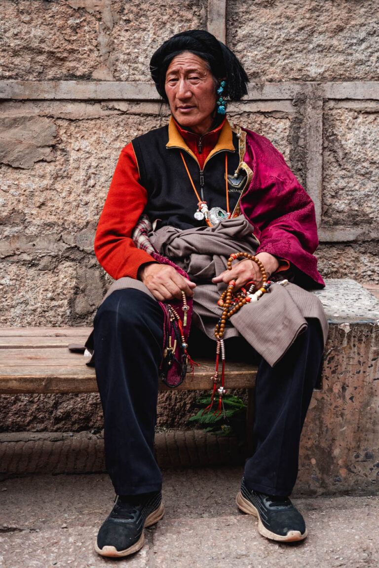 Khampa ethnic man seated with prayer wheel, Tibet China.