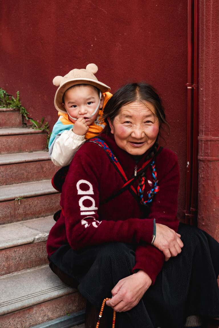 Mother and daughter laughing in maroon robes, Tibet.
