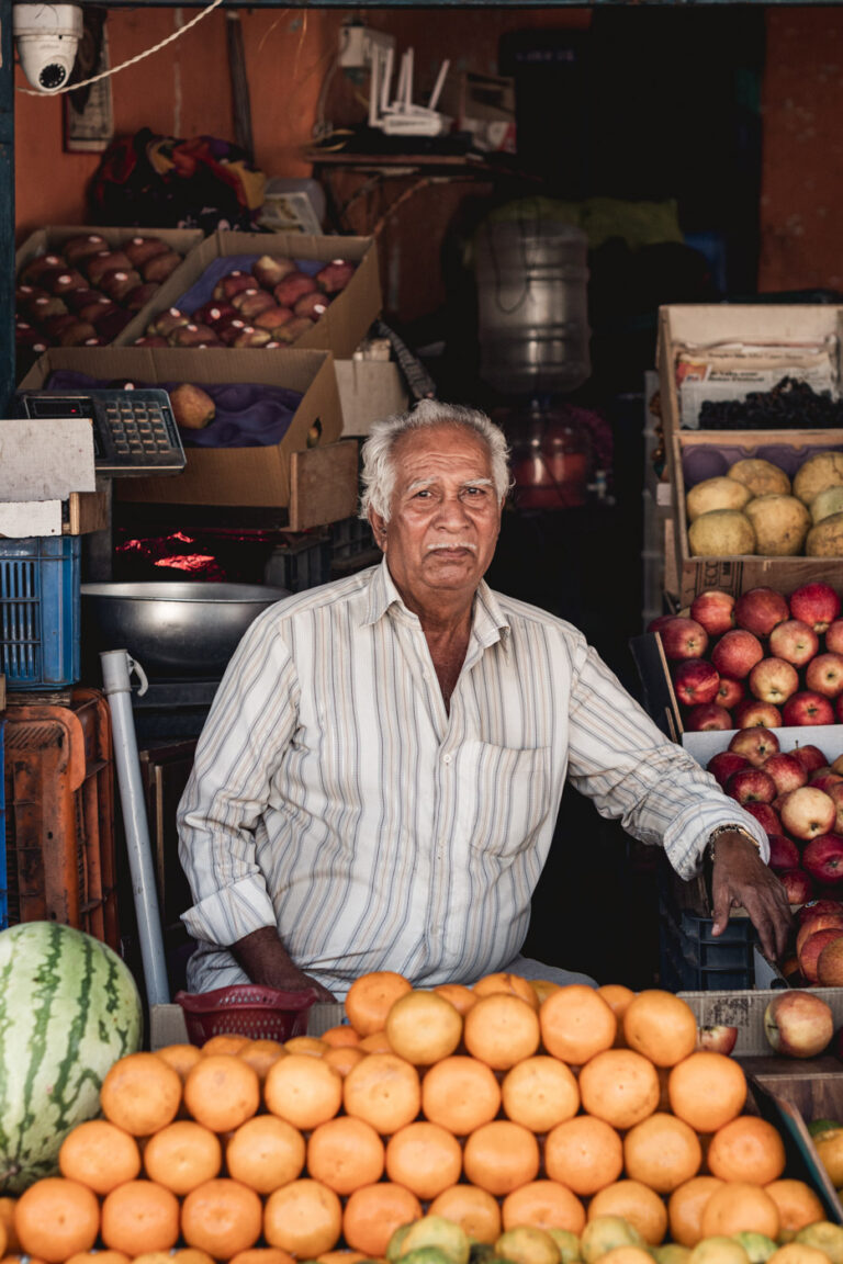 Fruit seller smiling behind his stall, India