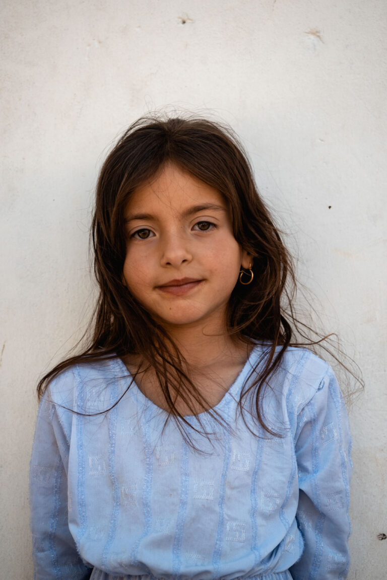 Young Yazidi girl with a serene expression sitting outdoors at Lalish in Kurdistan.