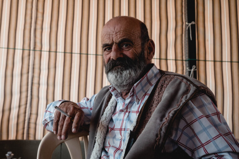 Portrait of a bearded Lebanese man in a modern jacket standing in a mountainous landscape near Batara Gorge.