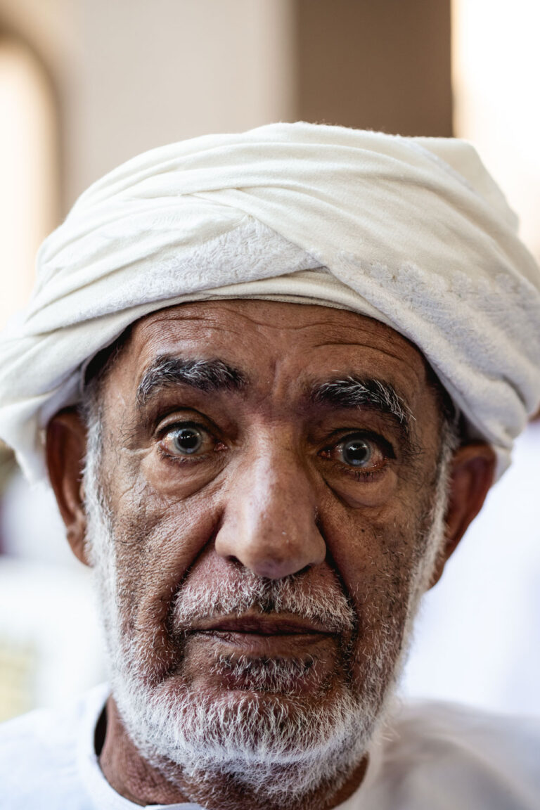 Close-up portrait of an elderly Omani man wearing a white turban and traditional dishdasha at Nizwa Friday Market