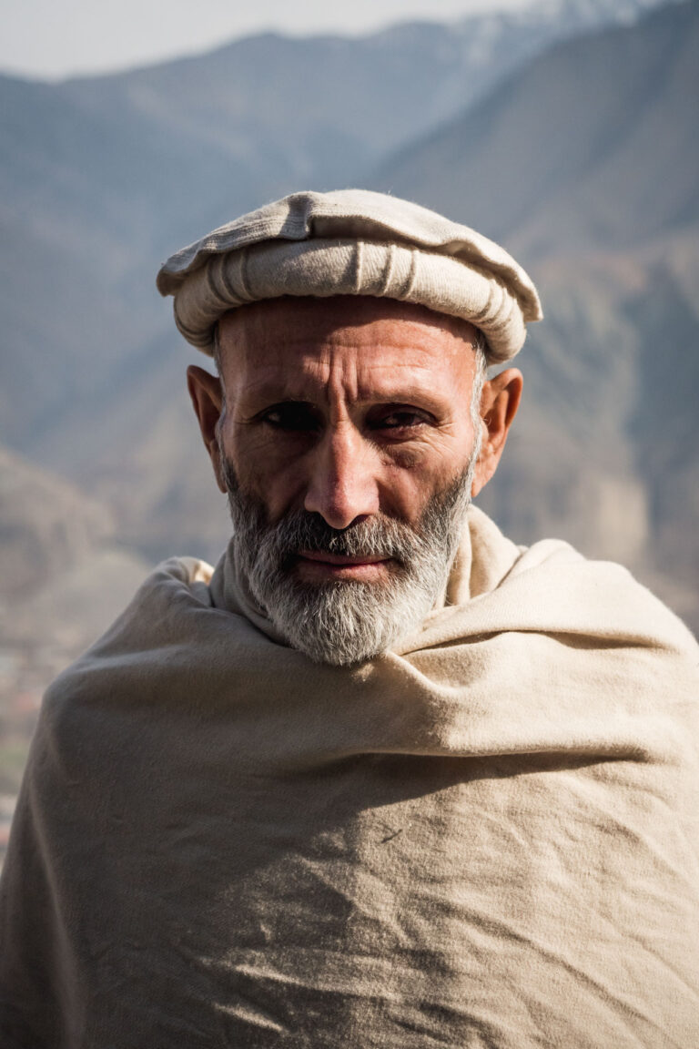 Portrait of an elderly Chitrali man wrapped in a thick woolen shawl in Chitral.