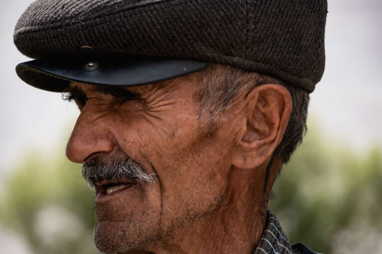 Elderly man wearing a dark cap gazing into the distance in Vrang, Wakhan Corridor.