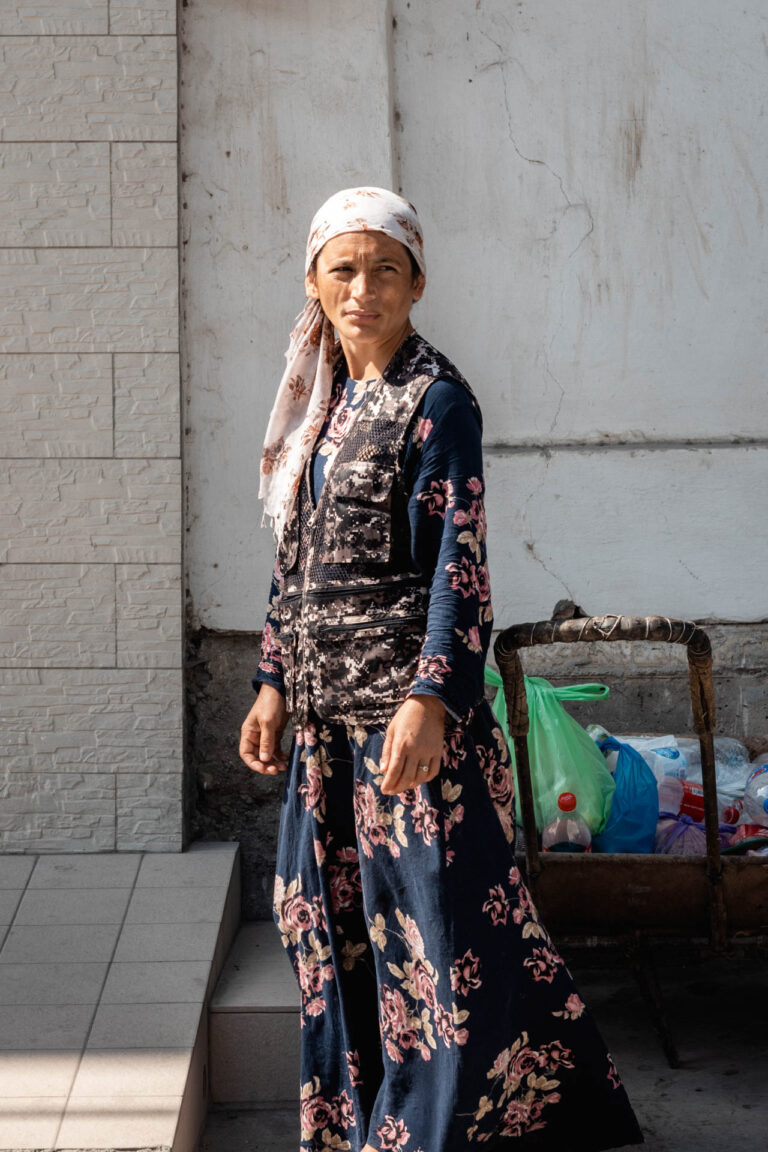 A young Uzbek woman standing in the street of Samarkand, wearing a pink scarf and a traditional dress, in Uzbekistan.