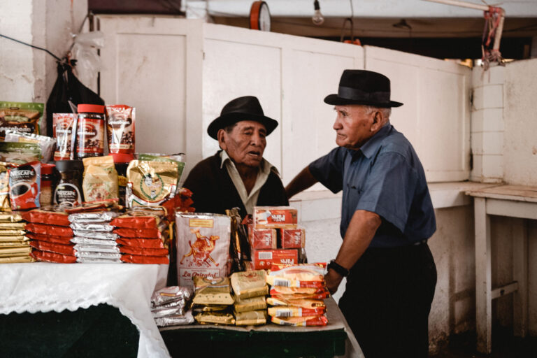 Local market scene with Bolivian men in traditional attire selling produce.
