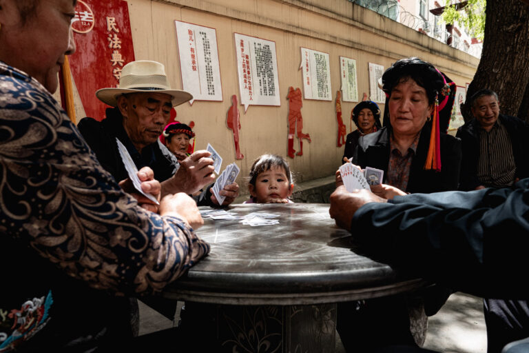Group of Gyarong women in traditional dress playing cards in Danba town.