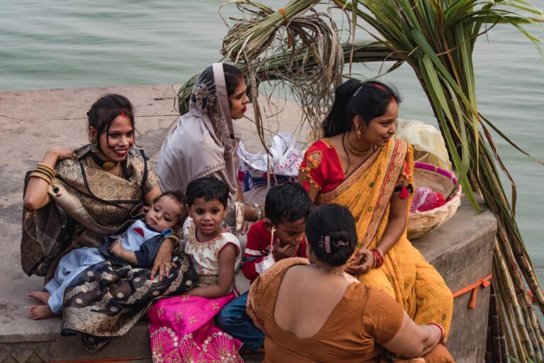 Hindu pilgrims sitting under a palm tree by the Ganges River in Varanasi.