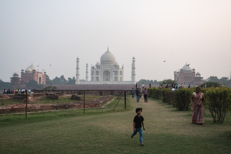 boy playing in a garden behing the taj mahal