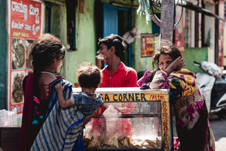Dalit children outside Mysore market — girl holding a baby, her sister staring at the camera.
