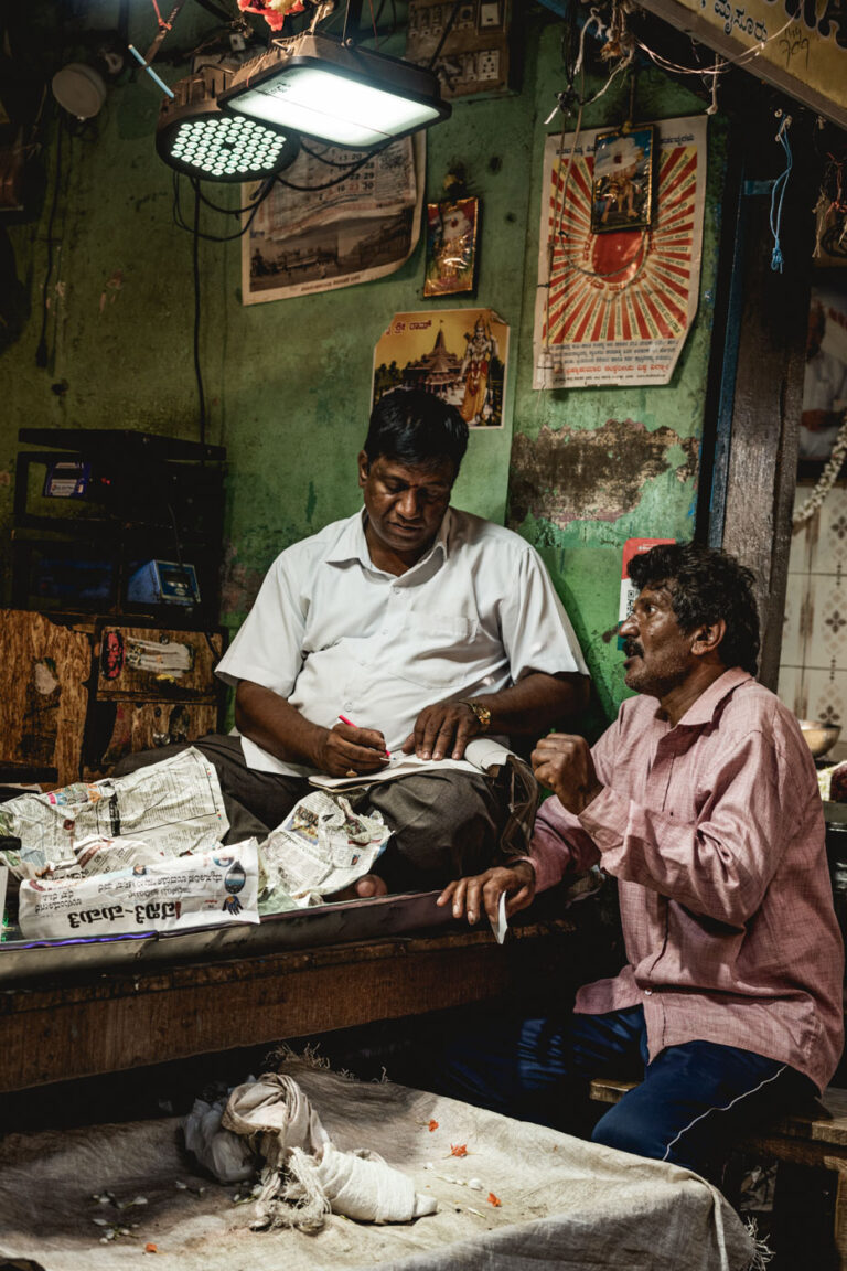 Fruit and vegetable market scene in Mysore, India — vendor and customer engaged in conversation.