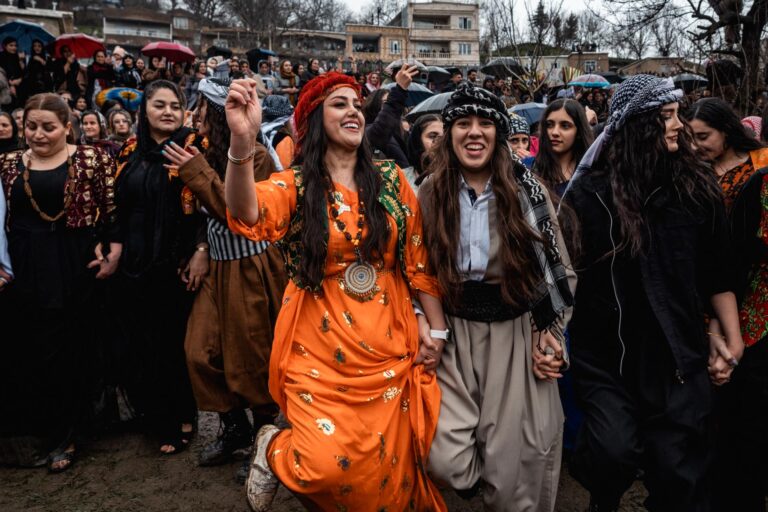 Kurdish women dancing and gathering in celebration of Nowruz amidst traditional attire.