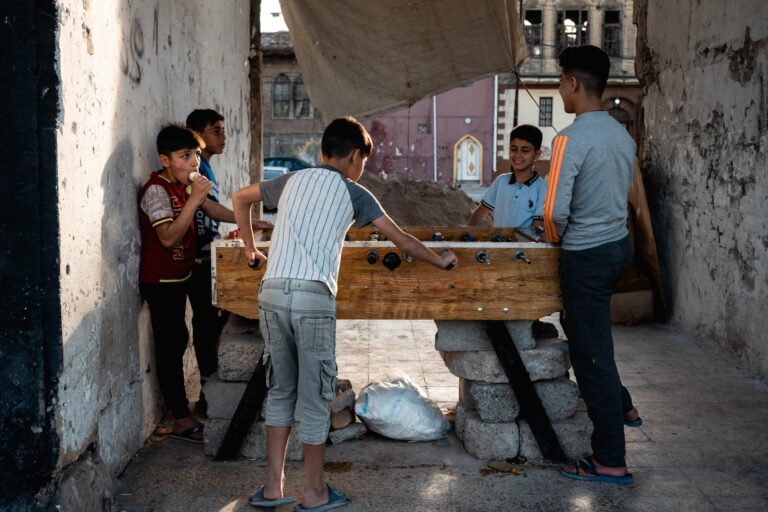 Iraqi kids playing foosball in a destroyed building at sunset in Mosul