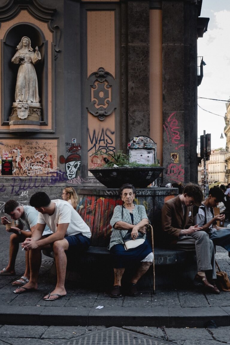 An elderly woman witting alone in vibrant place of Napoli