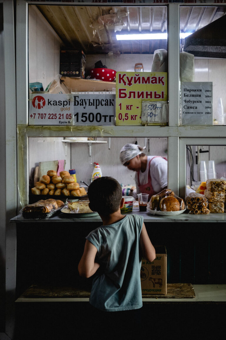 Market scene in Almaty, Kazakhstan: a young man waiting for his bread in front of a woman's shop
