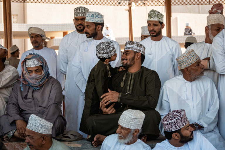 Father and son sharing a moment of connection amidst the crowd at the animal market in Nizwa