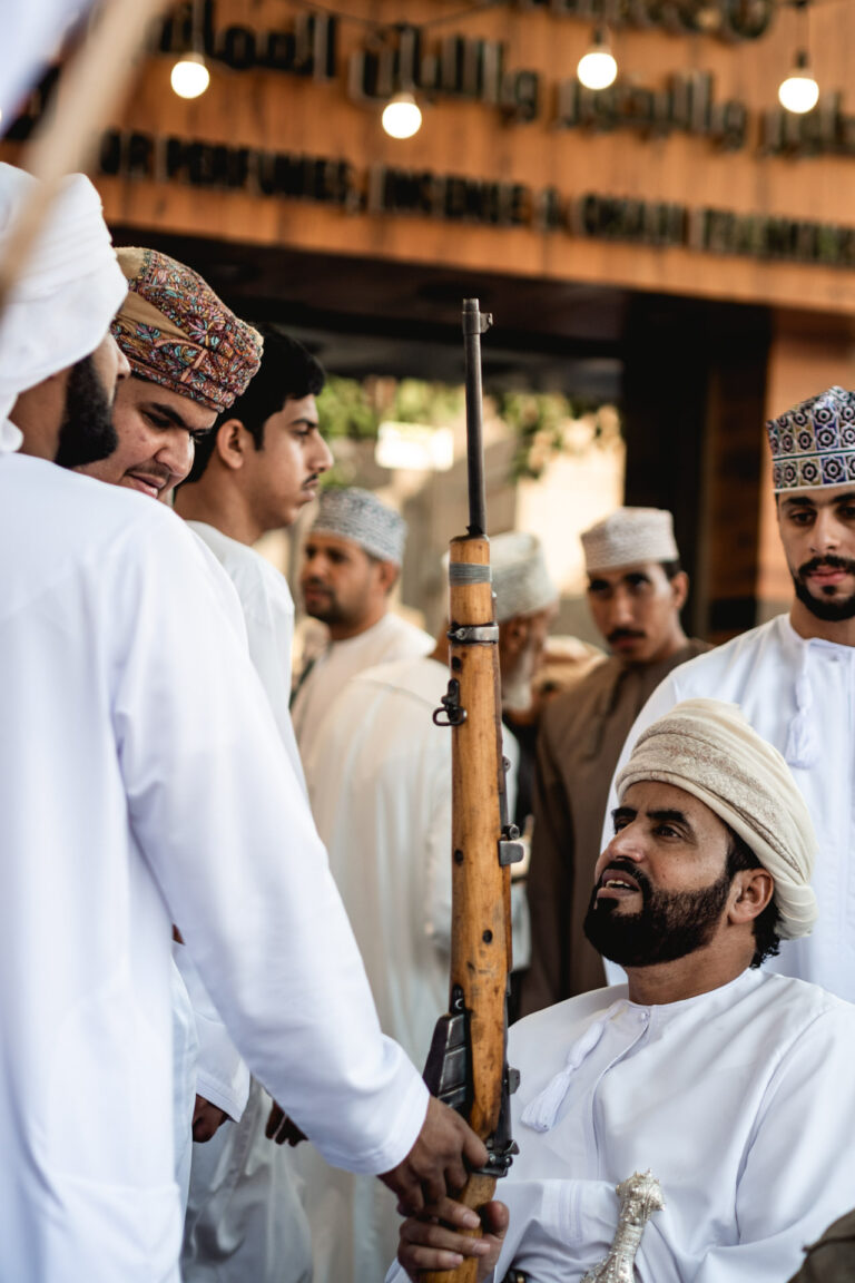 A group of Omanis in their traditional dishdashas, negotiating at the gun market in Nizwa