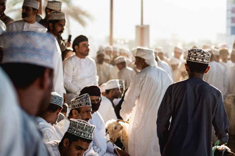 Omani men and children gathered around livestock at Nizwa’s historic market.