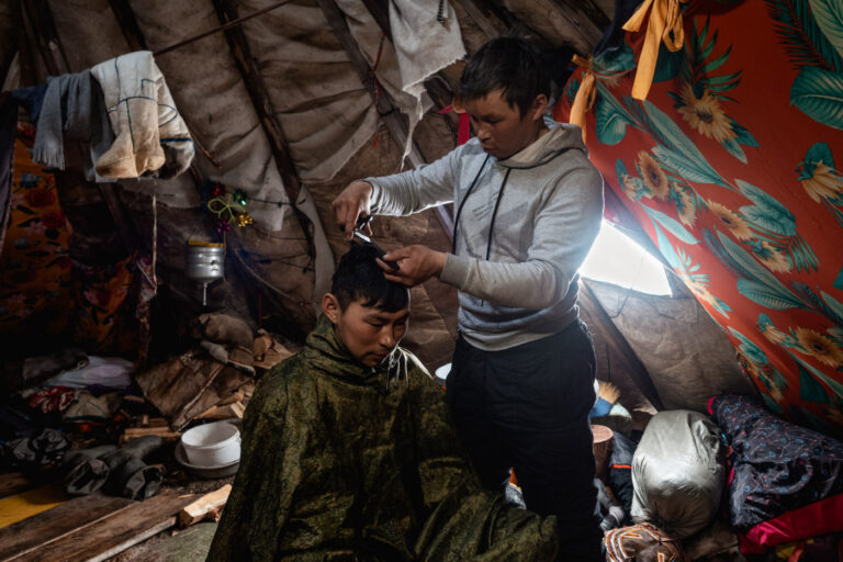 Nenets family sharing meal around warm fire inside their chum.