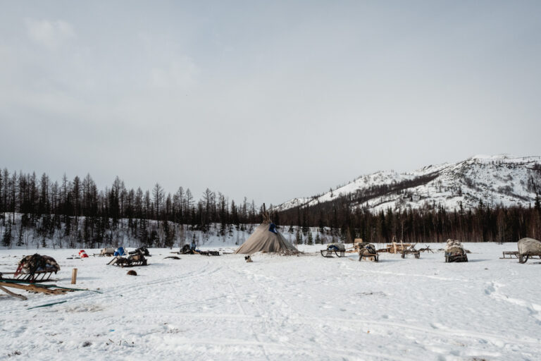 Frozen tundra landscape with wooden sled tracks cutting through snow.