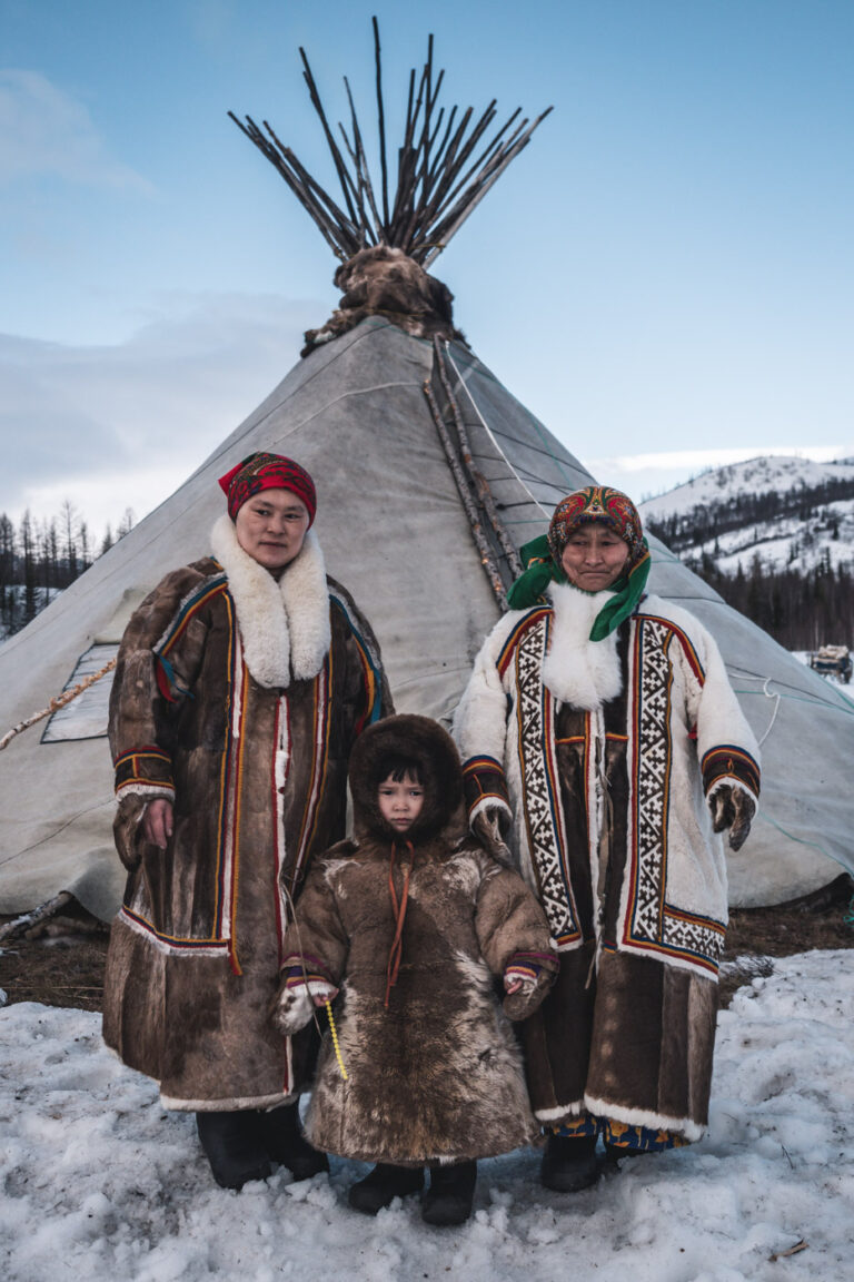 Nenets family posing in front of their reindeer-hide chum tent.
