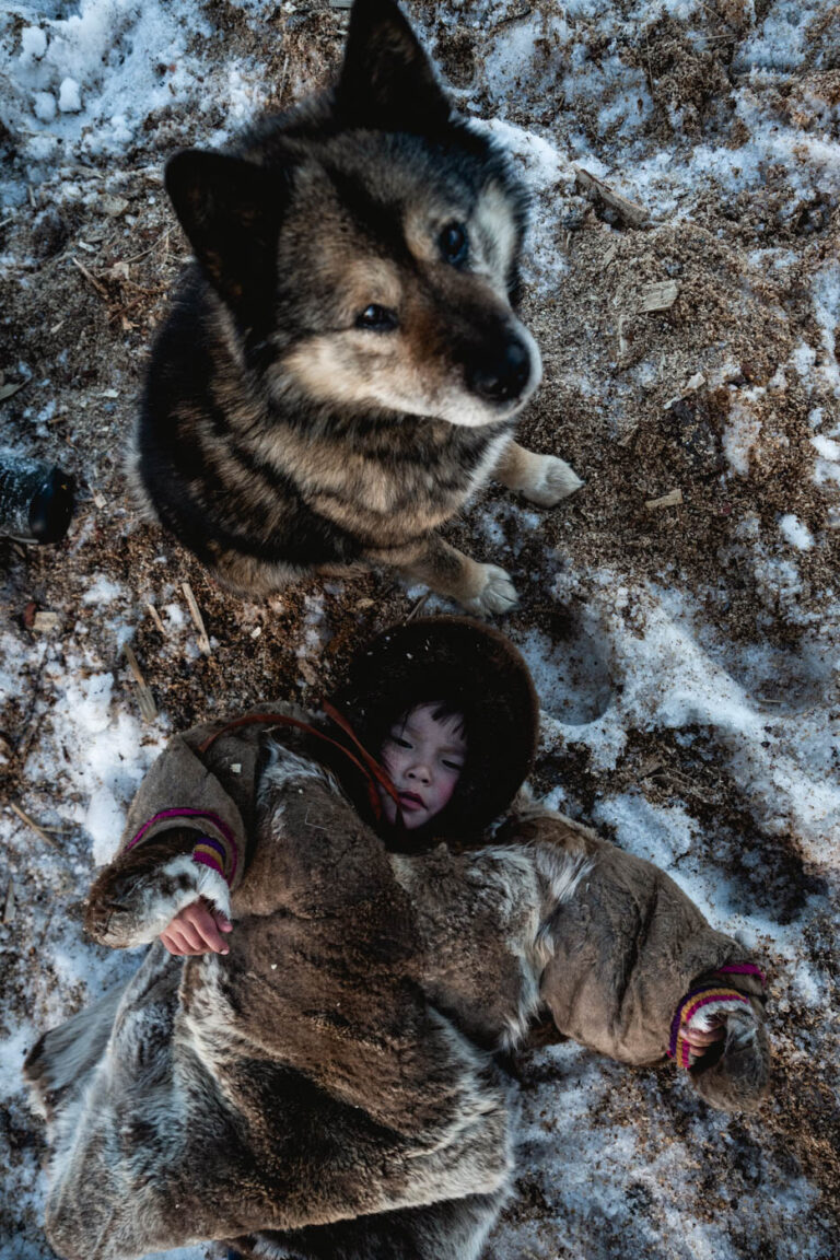 Top-down view of Nenets child wrapped in furs inside circular tent.