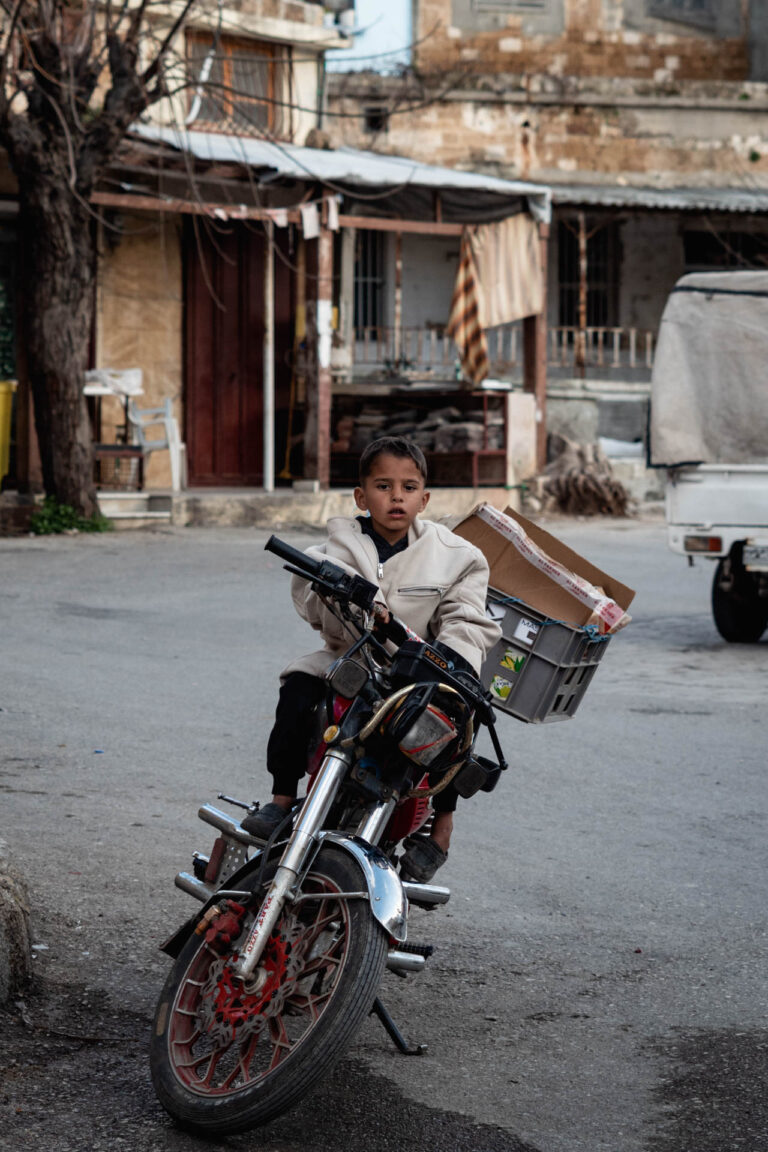 Young boy riding a motorcycle in a street in Tartus, Syria.